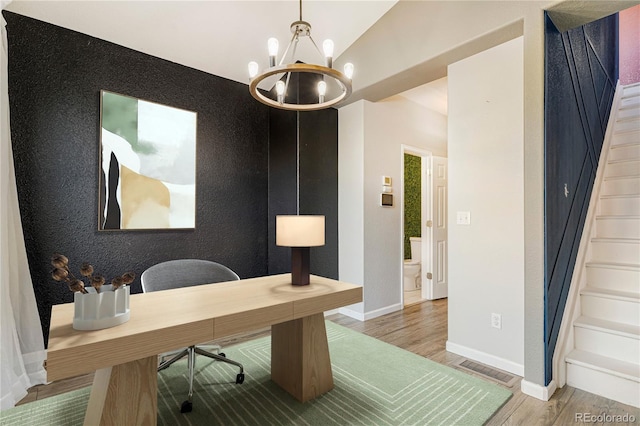 home office with wood-type flooring and an inviting chandelier