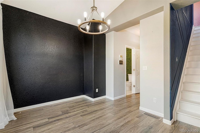 spare room with a chandelier and light hardwood / wood-style floors