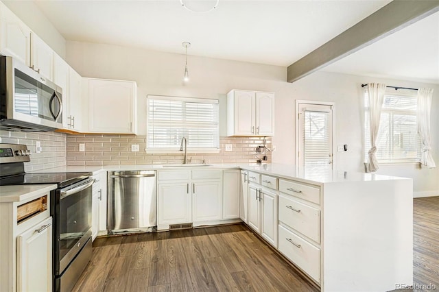 kitchen with sink, white cabinetry, hanging light fixtures, appliances with stainless steel finishes, and dark hardwood / wood-style flooring