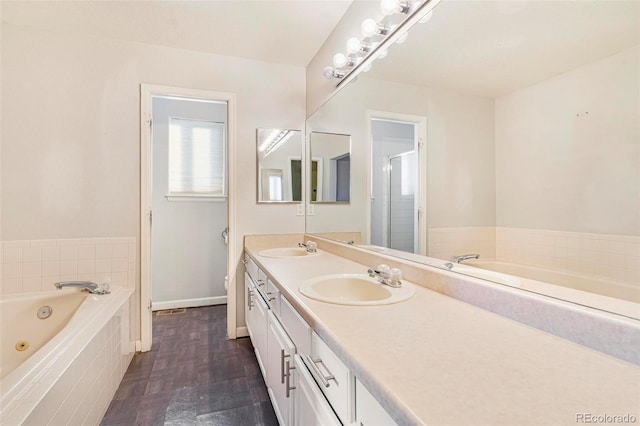 bathroom with vanity, tiled bath, and toilet