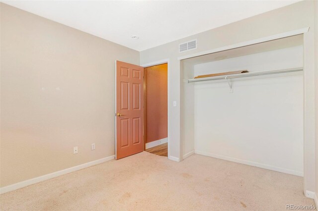 unfurnished bedroom featuring a closet and light carpet