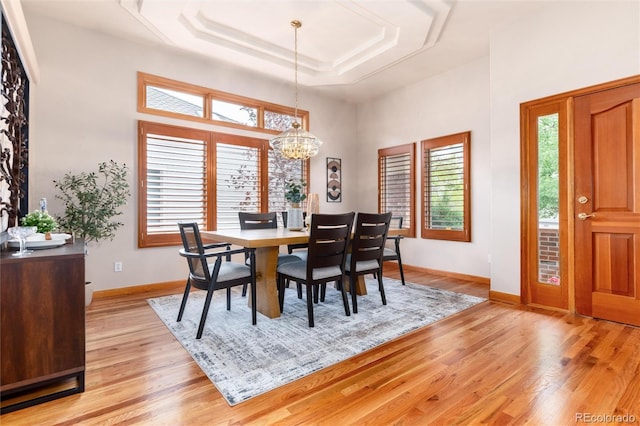 15851 Deer Ridge Dr, Morrison, CO 80465 - dining room with a chandelier, light wood-style flooring, a tray ceiling, baseboards, and a high ceiling