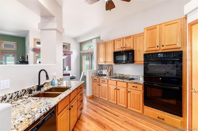 15851 Deer Ridge Dr, Morrison, CO 80465 - kitchen featuring black appliances, a sink, light wood finished floors, ceiling fan, and light stone counters