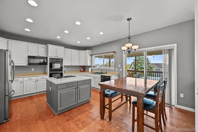 1120 N Calhan Ave, Castle Rock, CO 80104 - kitchen featuring black appliances, white cabinets, light countertops, a chandelier, and a kitchen island