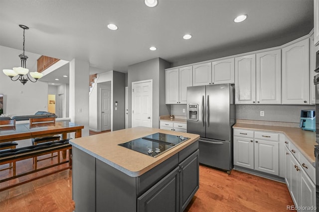 1120 N Calhan Ave, Castle Rock, CO 80104 - kitchen featuring stainless steel refrigerator with ice dispenser, black electric cooktop, white cabinetry, light wood finished floors, and a chandelier