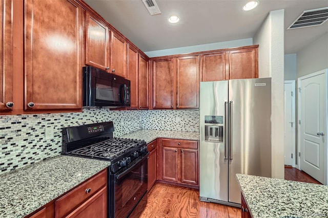 8883 White Prairie Vw, Colorado Springs, CO 80924 - kitchen featuring black appliances, light stone counters, light wood-style flooring, decorative backsplash, and recessed lighting