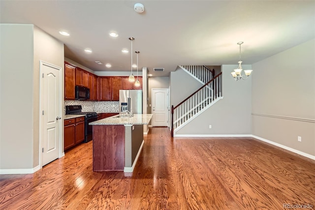 8883 White Prairie Vw, Colorado Springs, CO 80924 - kitchen featuring black appliances, wood finished floors, hanging light fixtures, tasteful backsplash, and recessed lighting