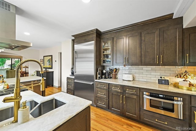 1414 S Vine St, Denver, CO 80210 - kitchen with appliances with stainless steel finishes, exhaust hood, backsplash, dark brown cabinetry, and recessed lighting