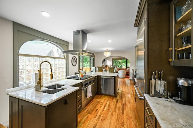 1414 S Vine St, Denver, CO 80210 - kitchen with island range hood, high end appliances, arched walkways, light wood-type flooring, and light stone countertops