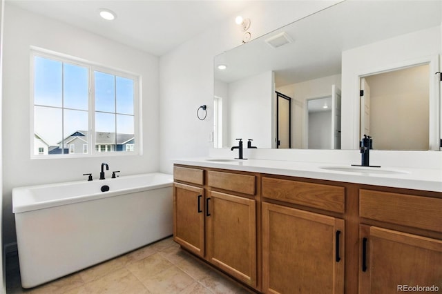 bathroom with a freestanding bath, double vanity, a shower stall, and a sink