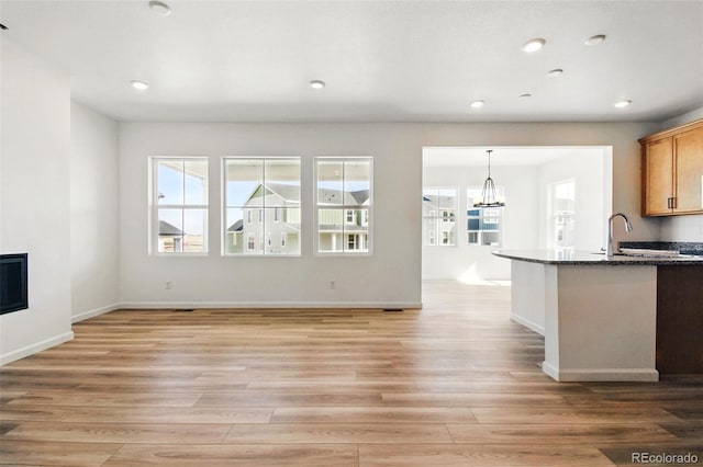 kitchen featuring a notable chandelier, a glass covered fireplace, a healthy amount of sunlight, and light wood-style floors