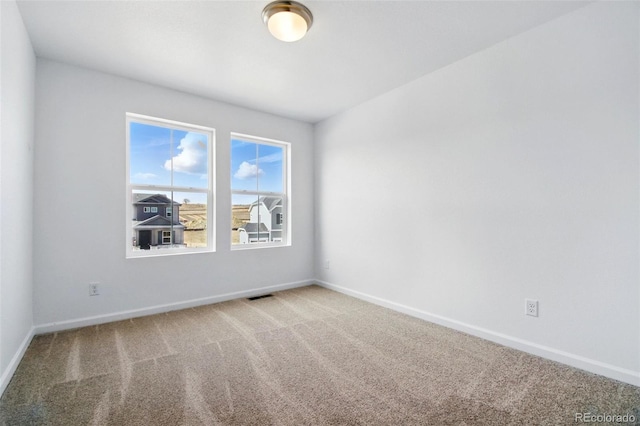 carpeted empty room featuring visible vents and baseboards