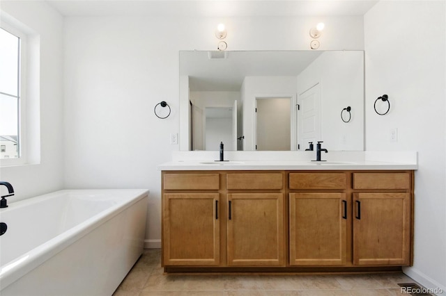 full bathroom featuring double vanity, a soaking tub, tile patterned flooring, and a sink