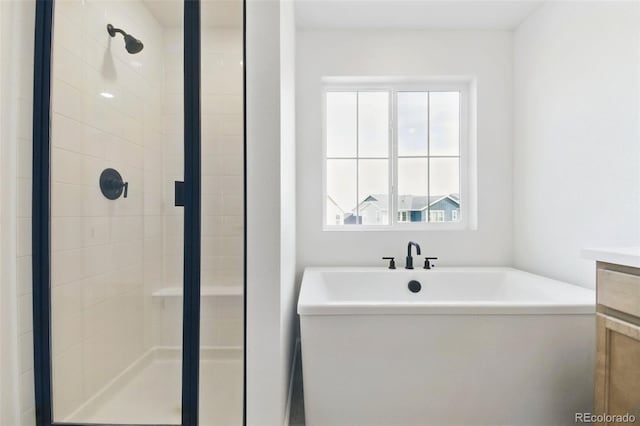 bathroom with vanity, a soaking tub, and a stall shower