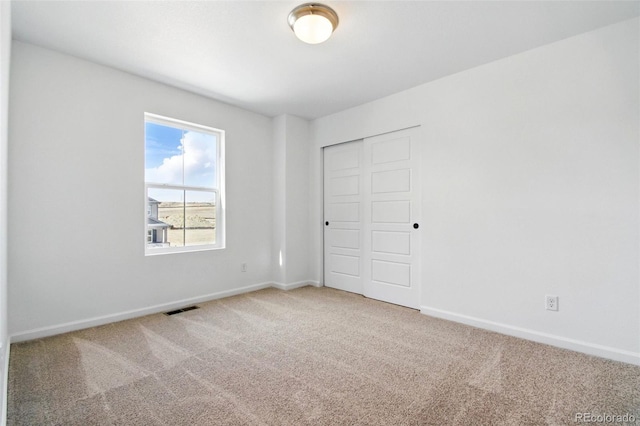 unfurnished bedroom with a closet, baseboards, visible vents, and carpet floors