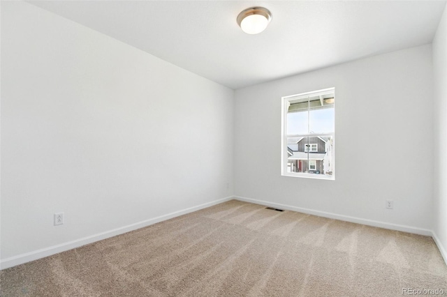 spare room featuring visible vents, baseboards, and light colored carpet