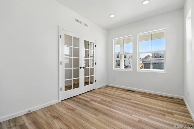 unfurnished room featuring visible vents, light wood-style flooring, french doors, and baseboards