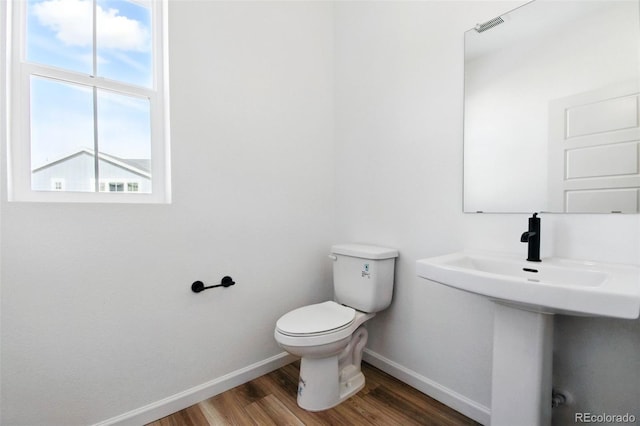 half bathroom featuring baseboards, toilet, and wood finished floors