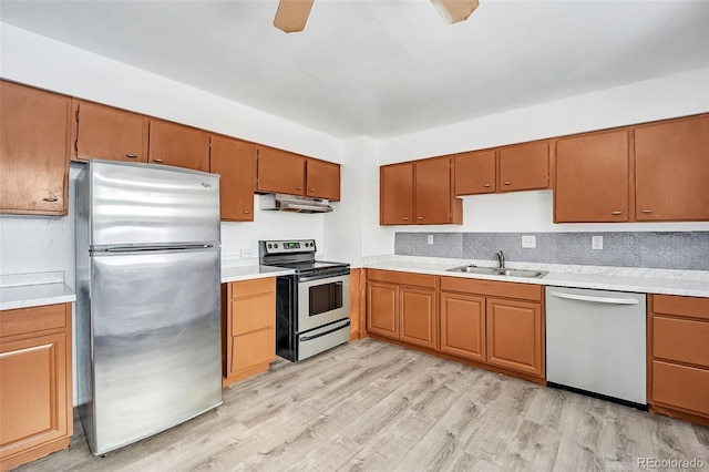 kitchen with sink, ceiling fan, backsplash, stainless steel appliances, and light wood-type flooring