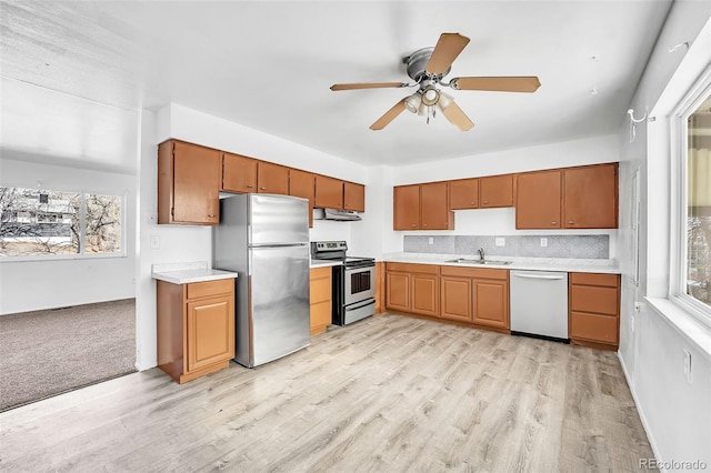 kitchen featuring sink, light hardwood / wood-style flooring, ceiling fan, stainless steel appliances, and tasteful backsplash