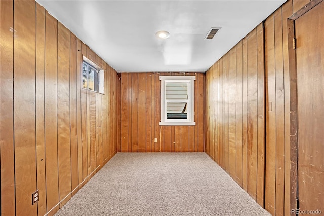 carpeted spare room featuring wooden walls