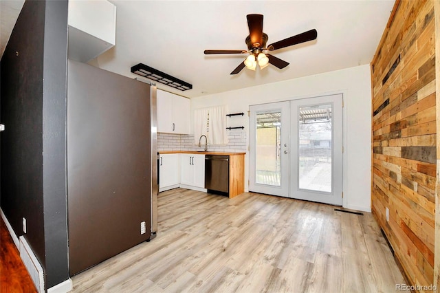1822 N Circle Dr, Colorado Springs, CO 80909 - kitchen with dishwashing machine, wood walls, a sink, white cabinets, and french doors