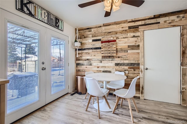 1822 N Circle Dr, Colorado Springs, CO 80909 - dining area with french doors, wood walls, light wood-style flooring, and a ceiling fan