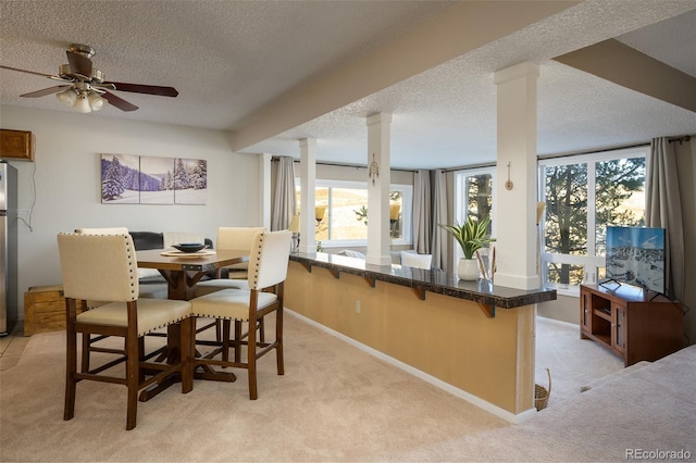 dining area featuring light carpet, a textured ceiling, and ceiling fan