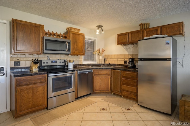 kitchen featuring decorative backsplash, appliances with stainless steel finishes, a textured ceiling, sink, and light tile patterned floors