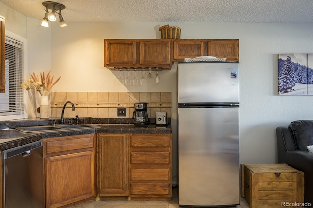 kitchen with appliances with stainless steel finishes, a textured ceiling, tasteful backsplash, and sink