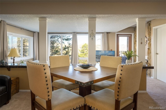 dining room with light carpet, a textured ceiling, and a healthy amount of sunlight