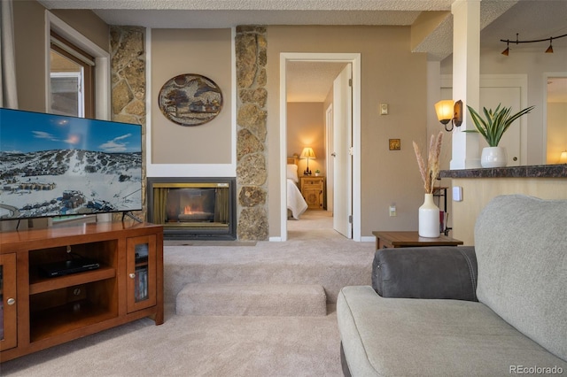 carpeted living room featuring a textured ceiling and a stone fireplace