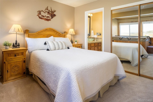 carpeted bedroom with ensuite bathroom and a closet