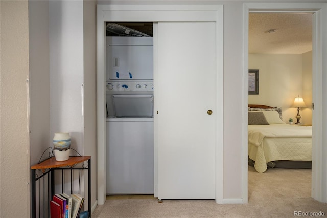 laundry room with light carpet, a textured ceiling, and stacked washer / dryer