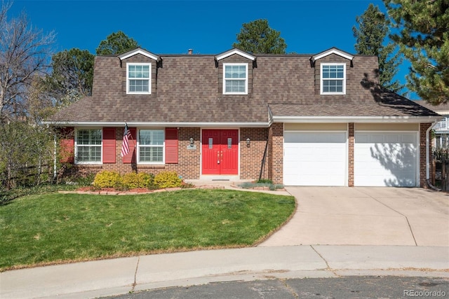 new england style home with brick siding, a shingled roof, a front yard, and concrete driveway