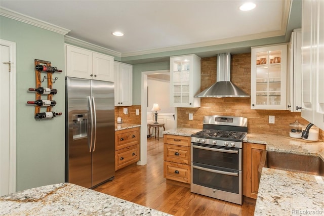 kitchen featuring crown molding, wood finished floors, recessed lighting, wall chimney exhaust hood, and stainless steel appliances