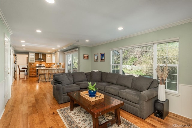 living area featuring crown molding, recessed lighting, and light wood-type flooring