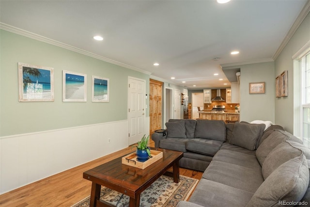 living room featuring crown molding, recessed lighting, wainscoting, and light wood-type flooring