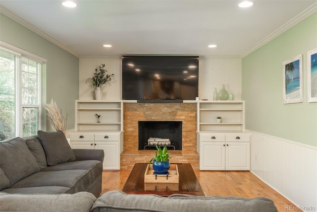 living room with recessed lighting, a wainscoted wall, ornamental molding, and light wood finished floors