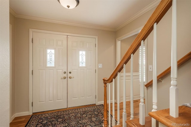 foyer featuring baseboards, ornamental molding, wood finished floors, and stairway