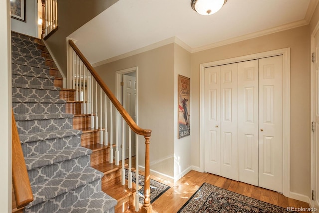 entrance foyer featuring crown molding, stairs, baseboards, and wood finished floors