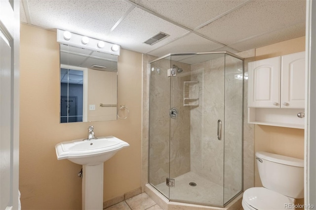 bathroom with visible vents, toilet, a drop ceiling, tile patterned floors, and a stall shower