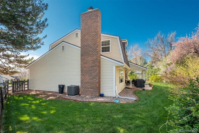 rear view of house featuring fence, central AC unit, a chimney, and a yard