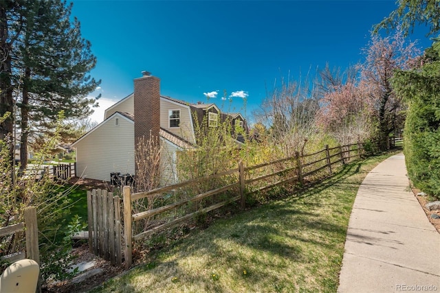 view of home's exterior with fence, a chimney, and a yard