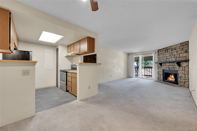 1830 S Pitkin Cir Unit B, Aurora, CO 80017 - kitchen with electric range, light colored carpet, a stone fireplace, under cabinet range hood, and open floor plan