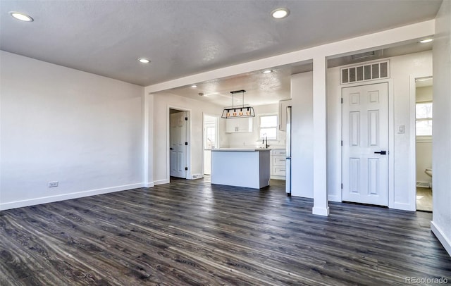 unfurnished living room featuring a textured ceiling, sink, and dark hardwood / wood-style floors