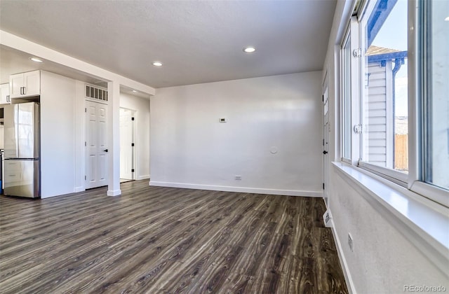 empty room featuring plenty of natural light and dark hardwood / wood-style floors