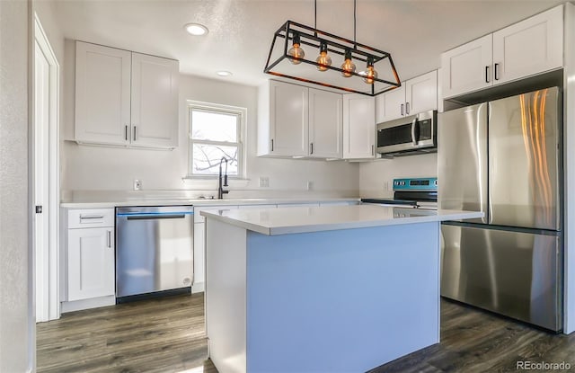 kitchen featuring decorative light fixtures, a kitchen island, dark hardwood / wood-style flooring, white cabinetry, and stainless steel appliances