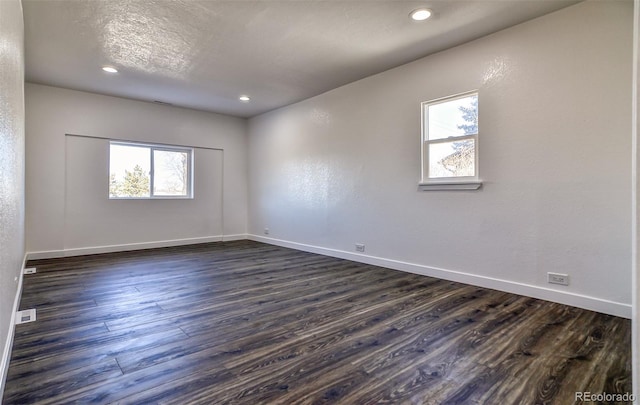 empty room with plenty of natural light and dark wood-type flooring