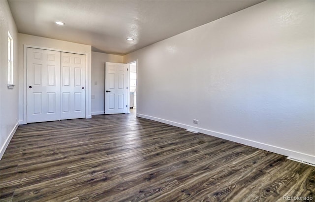 unfurnished bedroom featuring dark hardwood / wood-style flooring and a closet